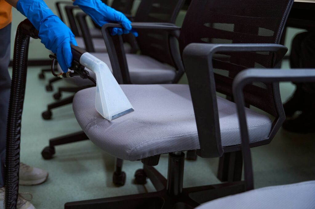 Certified cleaning specialist using upholstery vacuum-cleaner for chairs